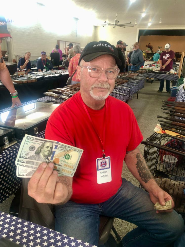 WWCA lifetime member Chuck Moline holds a fan of hundred dollar bills at his table on the show floor.