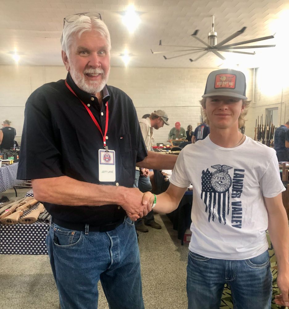 WWCA President Jeff Lane shakes hands with a young Lander Valley FFA member on the show floor.